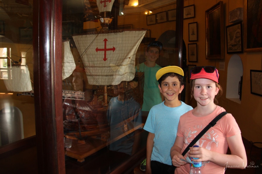 kids standing in front of model sail boat
