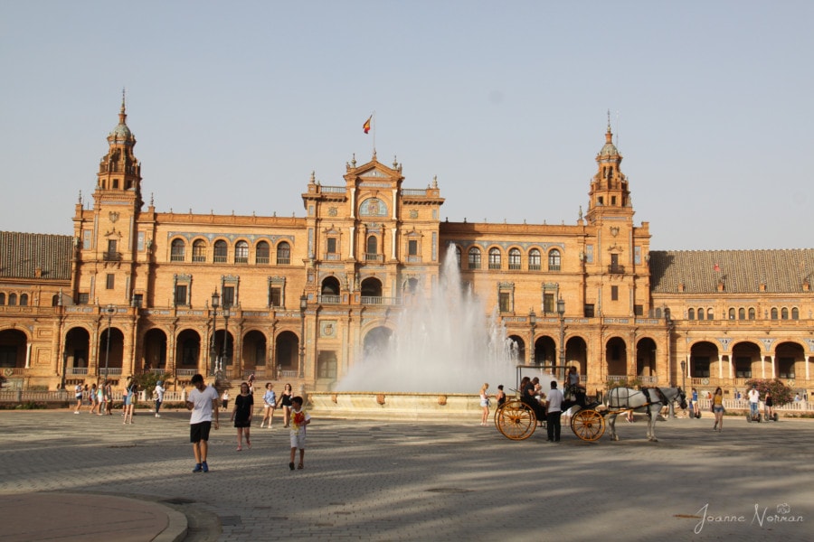 large stone building with fountain and horse drawn carriage