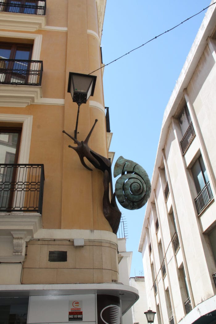 massive steel snail crawling on building