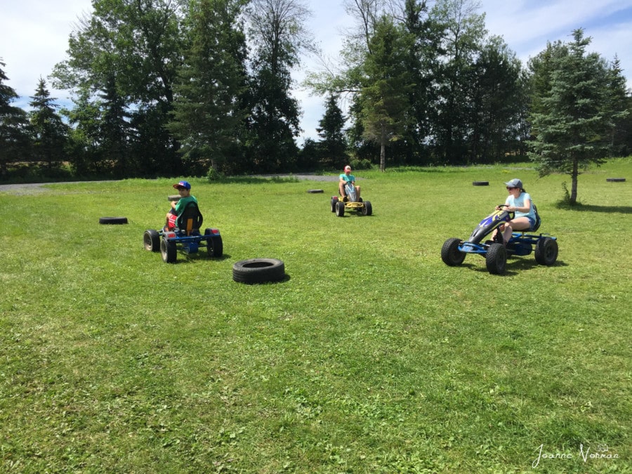 three kids riding go carts on lawn at farm great summer things to do in Ottawa with kids