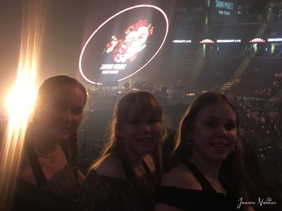 three teen girls inside dark concert with lights during Ottawa summer