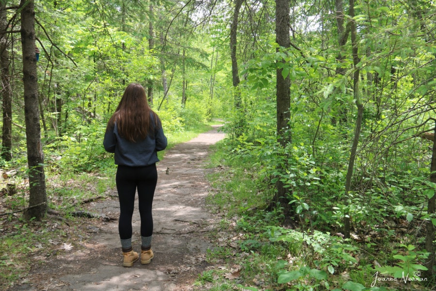 girl taking standing in path with chipmunk ahead