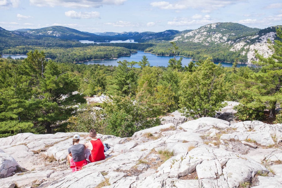 two people on large cliff overlooking lake below