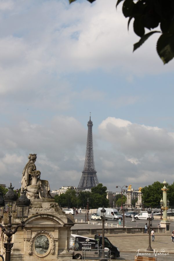 statue on corner of square lady with crown with eiffel tower in background