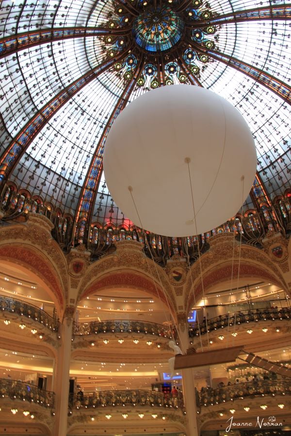 center of the mall with large white ball floating towards glass ceiling