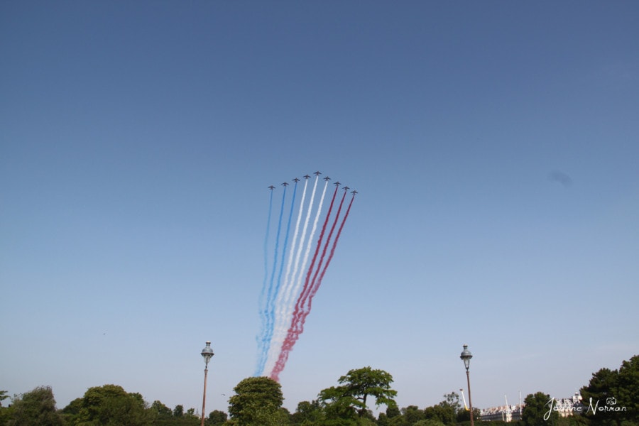 military acrobatic planes with red white and blue exhaust above gardens