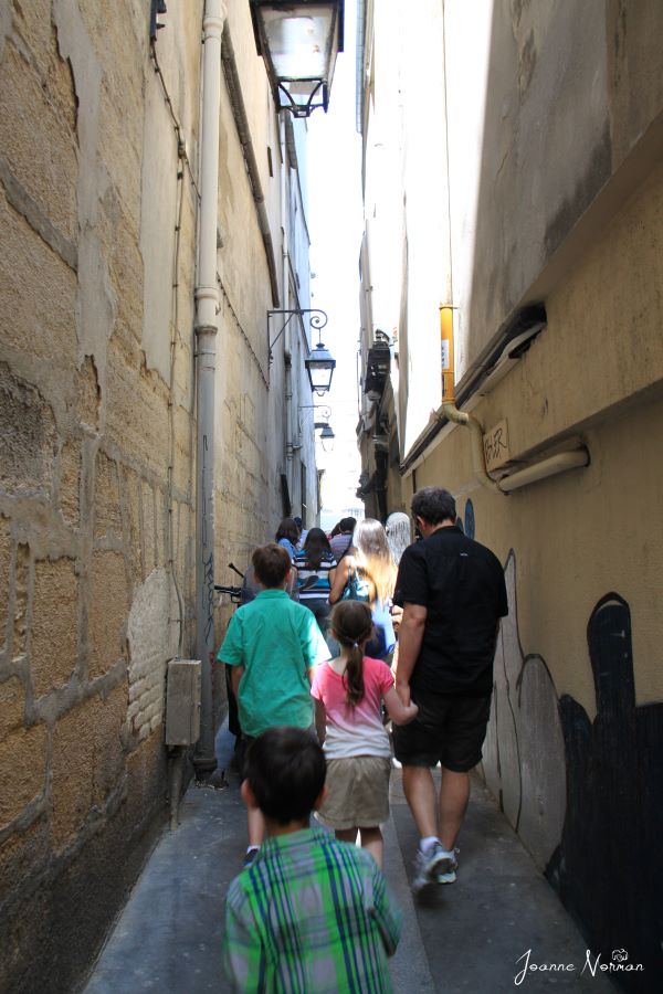 family walking through very narrow space between two buildings