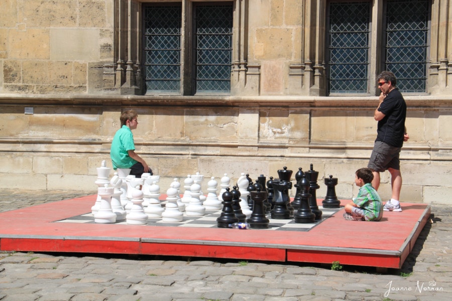 two boys and dad playing lifesize game of chess outdoors