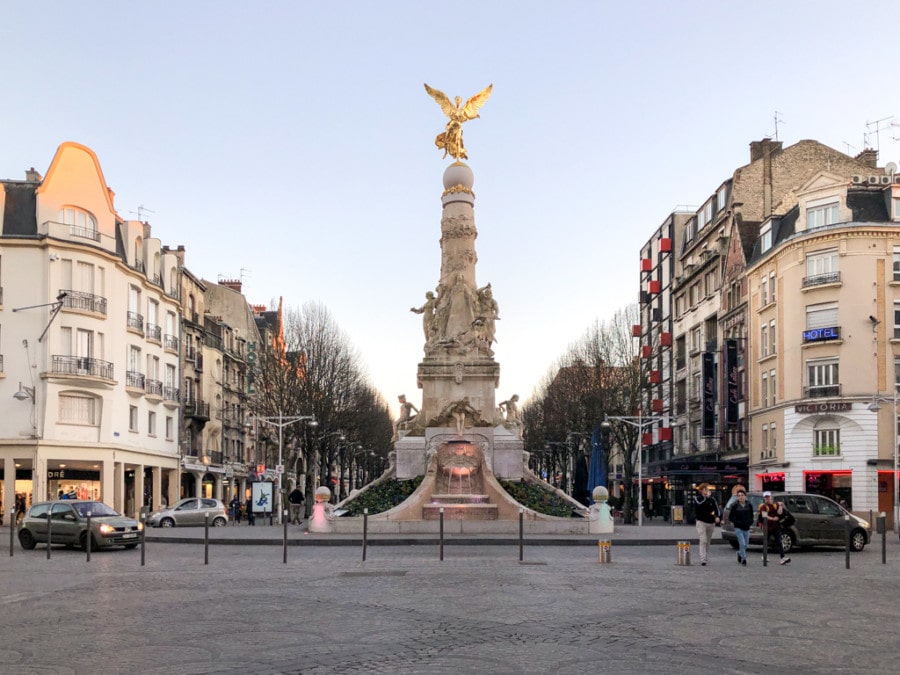 town square with large tower in center and golden bird on top daytrips from Paris to Reims