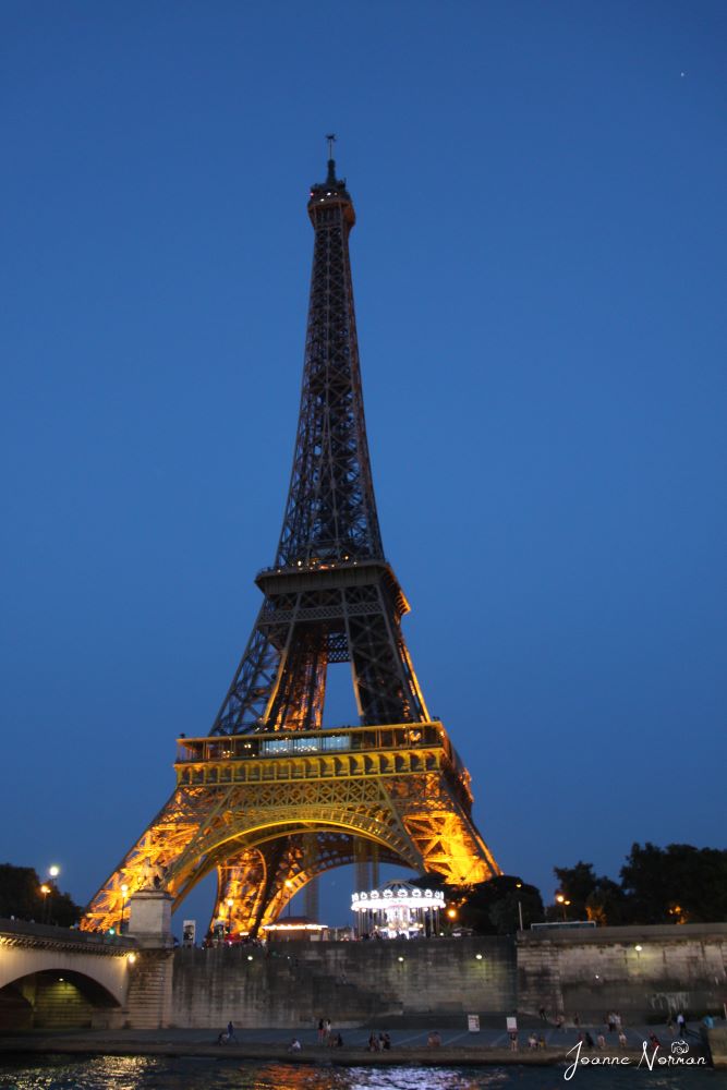 eiffel tower base glowing at night with dark blue sky paris itinerary