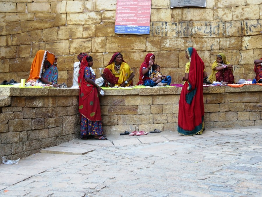 people in red and yellow traditional dress against white stone wall show autumn festival in India