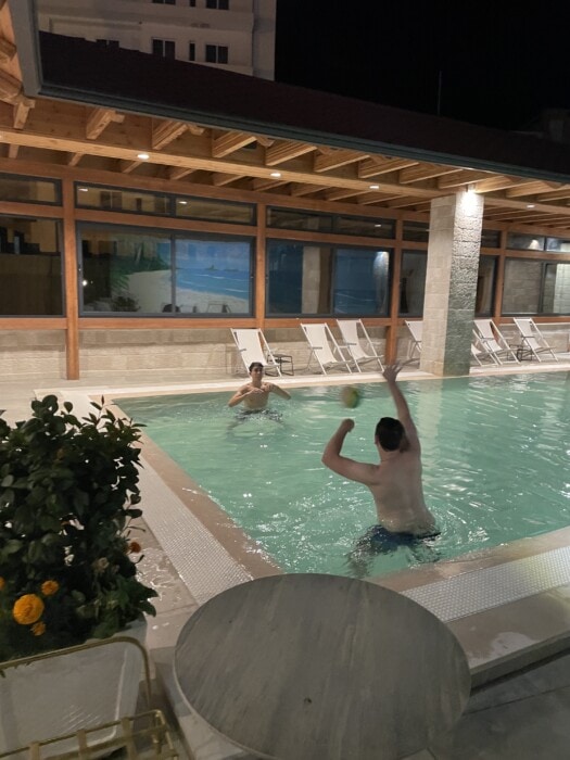  two boys playing ball in small hotel pool on roof