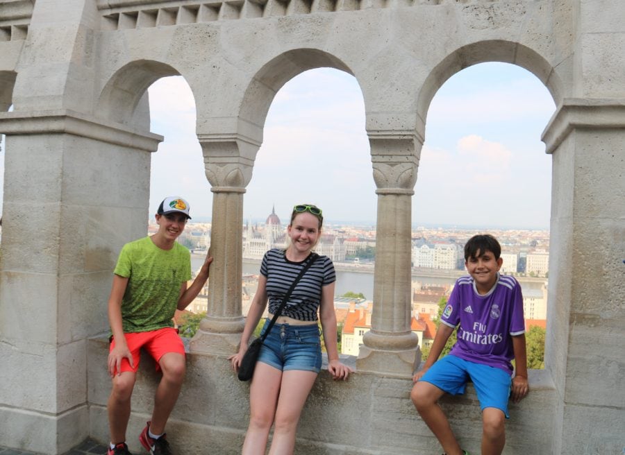 view of Budapest Parliament through arches of Fisherman Bastion with children sitting in each arch
