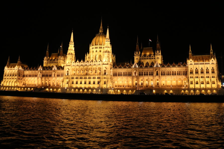 Best View of Budapest Parliament glowing at night with flags taken from boat on Danube